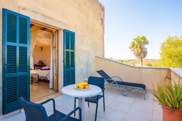 A balcony with a round table, blue chairs, and a fruit bowl. - AGROTURISMO MONDRAGO (Portopetro)