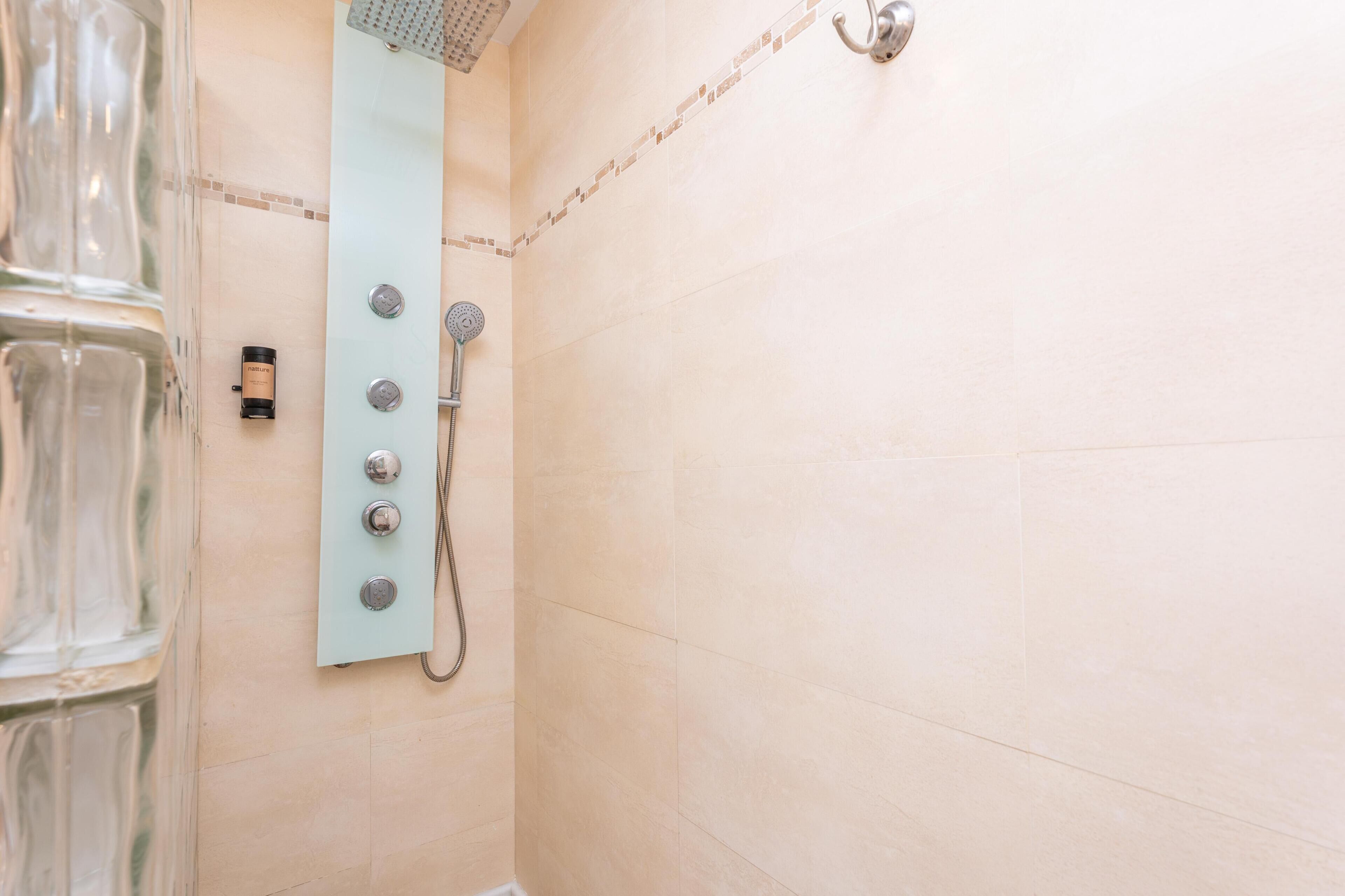 Eine Dusche mit Handbrause und Bedienfeld an der Wand.