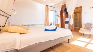 Ein Schlafzimmer mit einem großen Bett, einem Kleiderschrank, einem Sessel und einem Fenster.