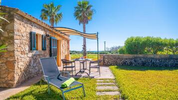Un edificio de piedra con un patio, mobiliario exterior y vistas del paisaje.