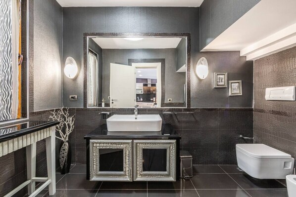 A modern bathroom with a large mirror, a white sink, and a toilet.