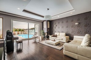 A spacious living room with a pool view, a fireplace, and a modern chandelier.