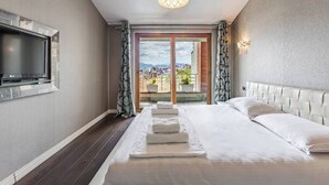 Ett hotellrum med en säng, en TV, utsikt över staden och en balkong.