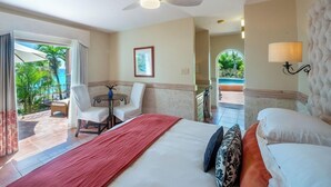 Habitación de hotel con cama, escritorio, silla, ventilador de techo, lámpara y vistas al exterior.