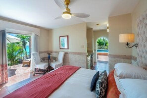 Habitación de hotel con cama, escritorio, silla, ventilador de techo, lámpara y vistas al exterior.