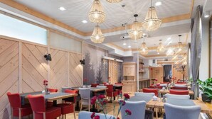 Un ristorante con diversi tavoli e sedie, pareti in legno e lampadari appesi.
