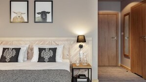 Una camera da letto con un letto, due quadri incorniciati, una lampada da comodino, un tavolino e una porta.