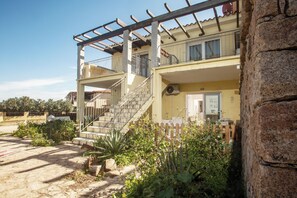 A two-story building with a balcony, a staircase, and a garden area. - Poseida Bay - Beautiful Sea View (Paduledda)