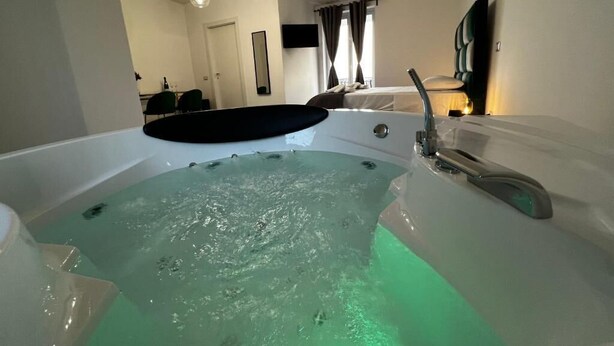 Ein Zimmer mit einer großen Badewanne, einem Essbereich und einem Bett.