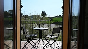 A balcony with two chairs and a table, overlooking a green landscape.