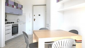 A compact kitchen with a dining area, including a stove, oven, sink, and a table with chairs.