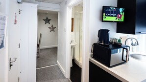 Ein Hotelzimmer mit Mikrowelle, Spüle, einer Stern-Dekoration an der Wand und einem Fernseher, der ein Spiel zeigt.