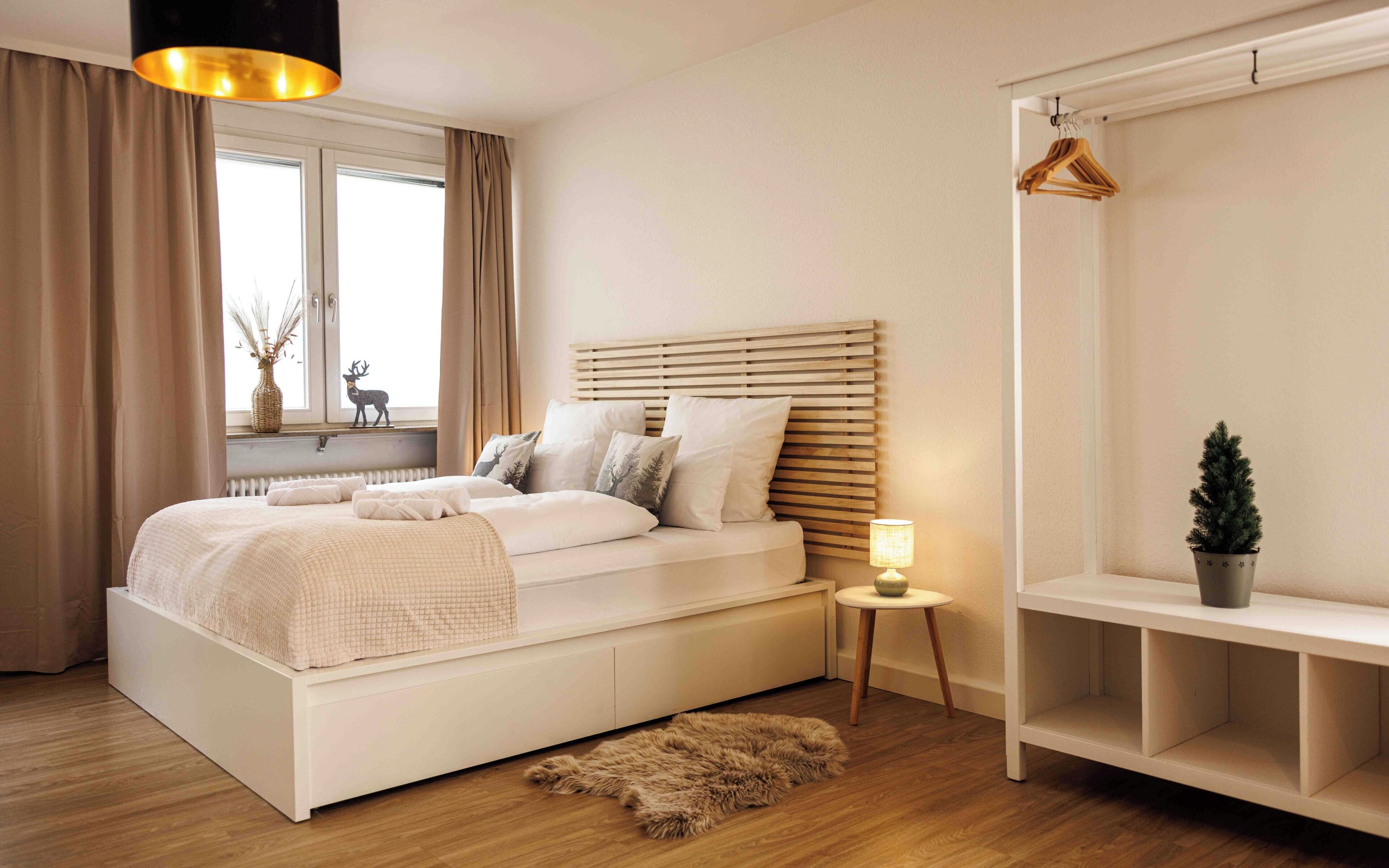 Une chambre à coucher avec un lit, une table de chevet, une lampe et un porte-manteau.