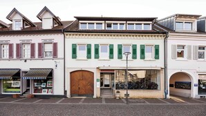 A building with a large wooden door, green shutters, and a bicycle in the window. - Vacation apartment Schwarzwaldnest 1 - central, accessible and quiet (Emmendingen)