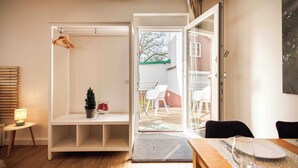 A modern interior with a white shelving unit, a small potted plant, and a dining area with a table and chairs. - Vacation apartment Schwarzwaldnest 1 - central, accessible and quiet (Emmendingen)