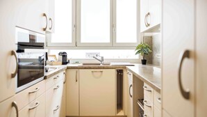 A kitchen with white cabinets, a sink, a stove, and a window above the sink. - Vacation apartment Schwarzwaldnest 1 - central, accessible and quiet (Emmendingen)