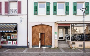Un edificio con una puerta de madera grande, un escaparate con toldo a rayas y un espacio para estacionar bicicletas.