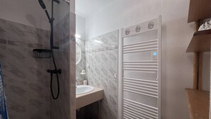 Casa de banho com chuveiro, lavatório e suporte para toalhas.