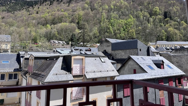 Área residencial com casas de telhados inclinados, algumas com claraboias, e uma montanha arborizada ao fundo.