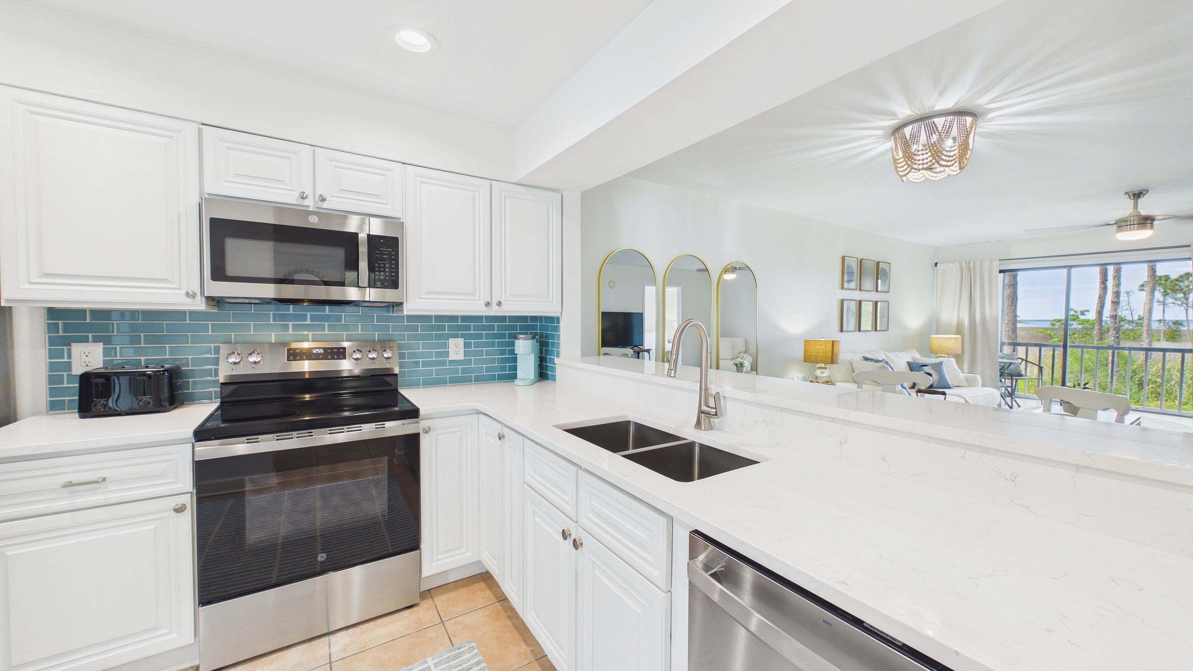 A modern kitchen with stainless steel appliances, a large window, and a balcony with a view.