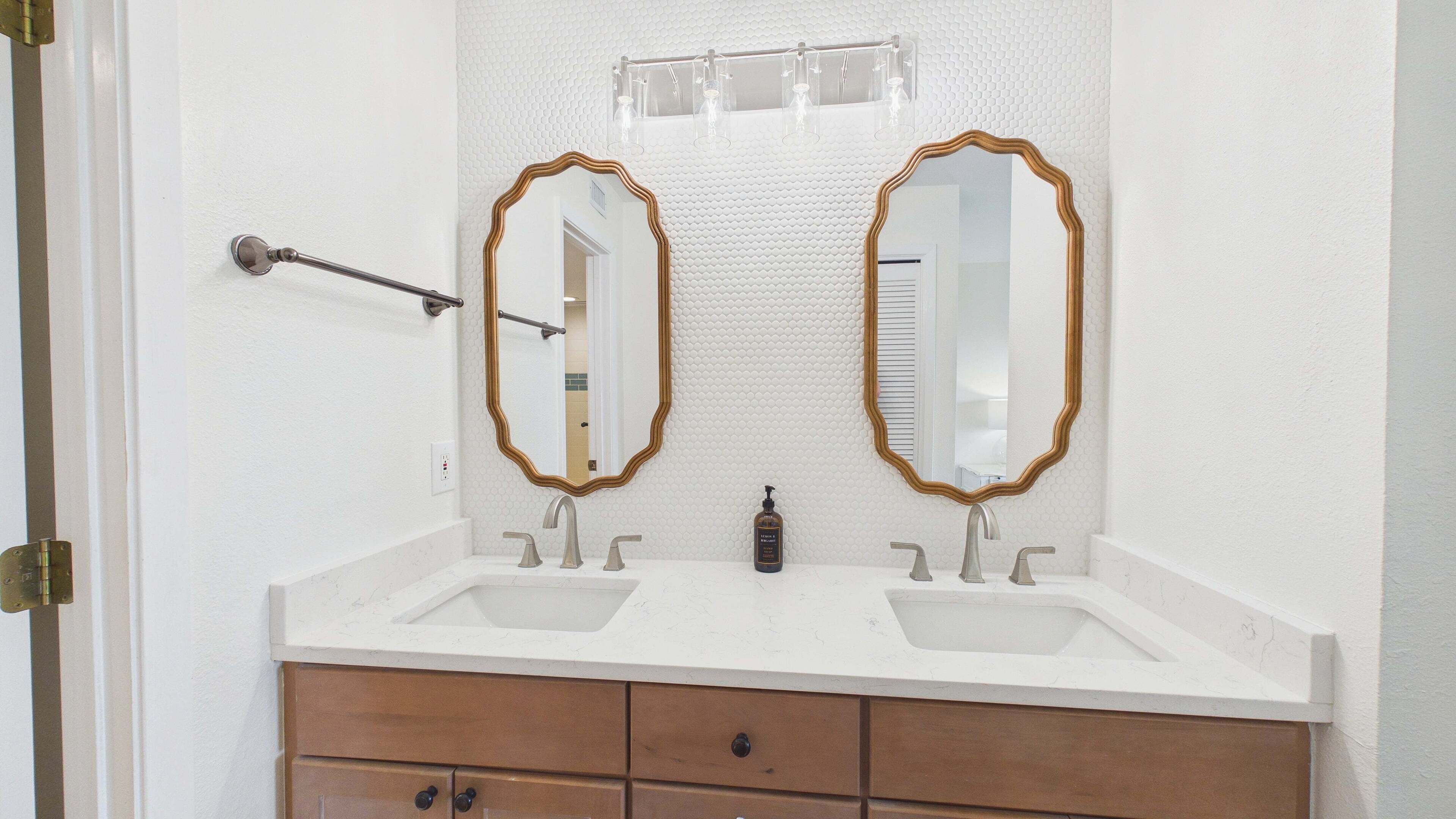 A bathroom with two sinks, a mirror, and a towel rack.