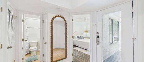 A hotel room with a bathroom, a large mirror, a bed, and a view of the outside.