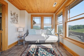 Een slaapkamer met een bed, vloerkleed, lamp en een kunstwerk aan de muur.