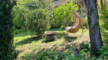 Un jardin avec une balançoire, une petite brouette et un arbre.