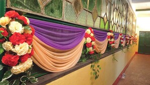 A hallway with a green wall, a patterned window, and a series of draped fabric and floral arrangements. - Innra Hotel Kolkata (Kolkata)