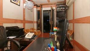 A room with a desk, computer, chair, fan, and a small Indian flag. - Innra Hotel Kolkata (Kolkata)
