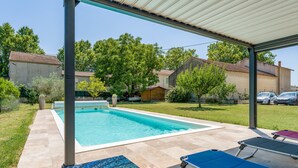 A covered outdoor swimming pool with lounge chairs and a mosaic tile rug. - New Studio at the Gateway to the Alpilles with Pool and Large Garden (Noves)