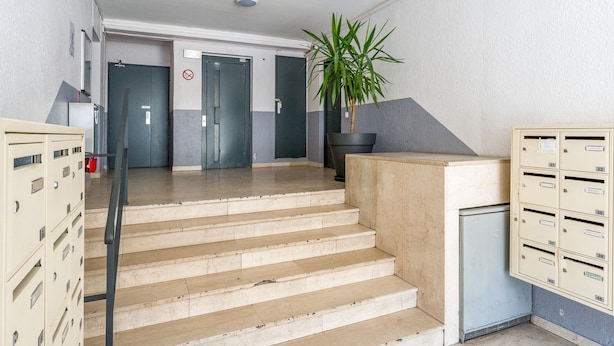 A hotel lobby with a staircase, a reception desk, a potted plant, and a row of mailboxes. - Cozy Studio in the Heart of Avignon (Avignon)