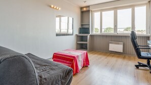 A room with a bed, a desk, a chair, a TV, and a window with a view. - Cozy Studio in the Heart of Avignon (Avignon)