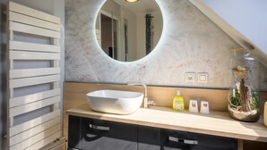 A modern bathroom with a white vessel sink, a round mirror, and a glass terrarium on the countertop. - Guest Room 'Chambre Marguerite' with Shared Pool, Terrace and Wi-Fi (Sélestat)