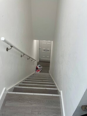 Un vestíbul estreta amb barana, graons de fusta i una porta blanca a dalt.