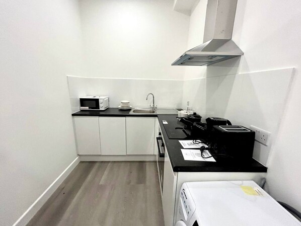 A compact kitchen with white cabinets, a microwave, a coffee maker, and a toaster.