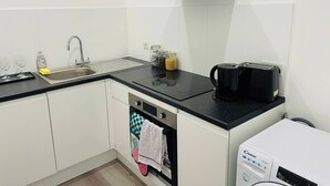 Cozinha compacta com pia, cafeteira e máquina de lavar louça.