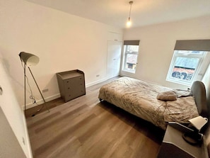 A bedroom with a bed, a dresser, a lamp, and a window.