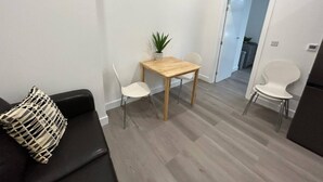 Uma sala moderna com um sofá, uma mesa de jantar com cadeiras e uma porta de entrada para outro cômodo.