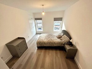 A bedroom with a bed, two windows, a ceiling light, and a small desk. - Beautiful Place to Stay (London)