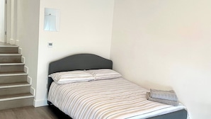 A bedroom with a bed, a light fixture, a mirror, and a staircase. - Beautiful Place to Stay (London)