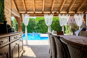 A covered outdoor area with a pool, wicker furniture, and a wooden ceiling. - Guest Room “Chambre Tulipe” with Shared Pool, Terrace, and Wi-Fi (Sélestat)