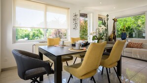 Uma área de refeições com mesa, cadeiras e vista para o verde lá fora.
