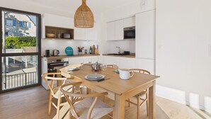 Eine moderne Küche mit Holzschränken, einem Esstisch mit Stühlen und einer Pendelleuchte.