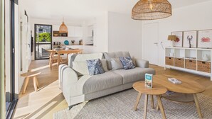 Ein modernes Wohnzimmer mit Sofa, Couchtisch und Essbereich mit Tisch und Stühlen.