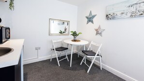A small room with a white table, two chairs, a potted plant, a framed picture, and decorative stars on the wall. - Guestz at The Wellington (Blackpool)