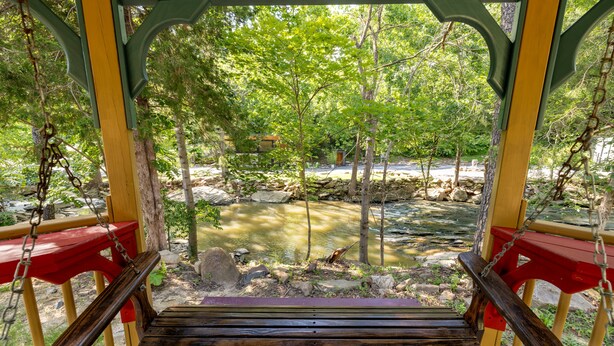 Un puente colgante de madera sobre un arroyo, con vistas a un área boscosa.