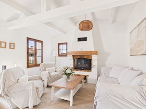 A room with a fireplace, striped furniture, a wooden table, and a hanging light fixture. - House for 6 - Garden - Near Town Centre (Noirmoutier-en-l´Ile)