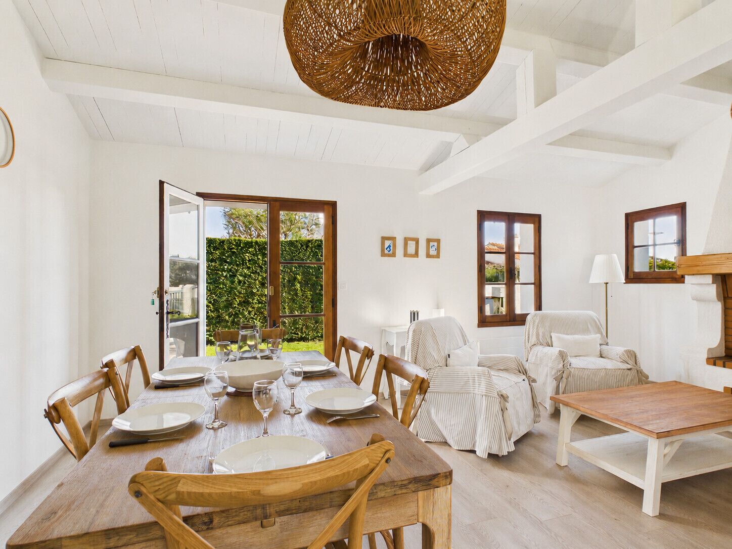 Un coin repas avec une table en bois, dressée pour six personnes, entourée de chaises.