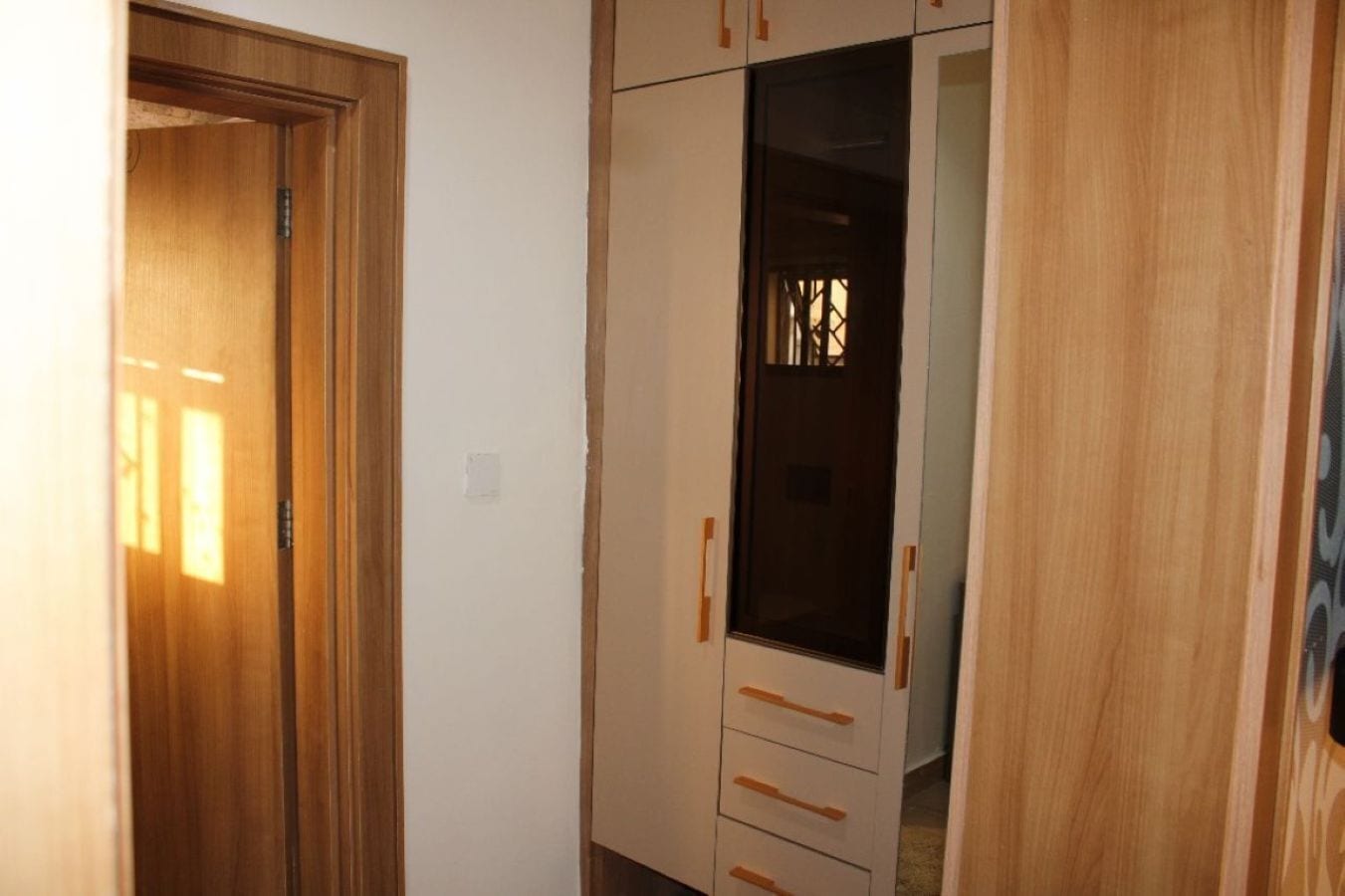 A hallway with wooden doors and a wardrobe with a mirror and drawers.